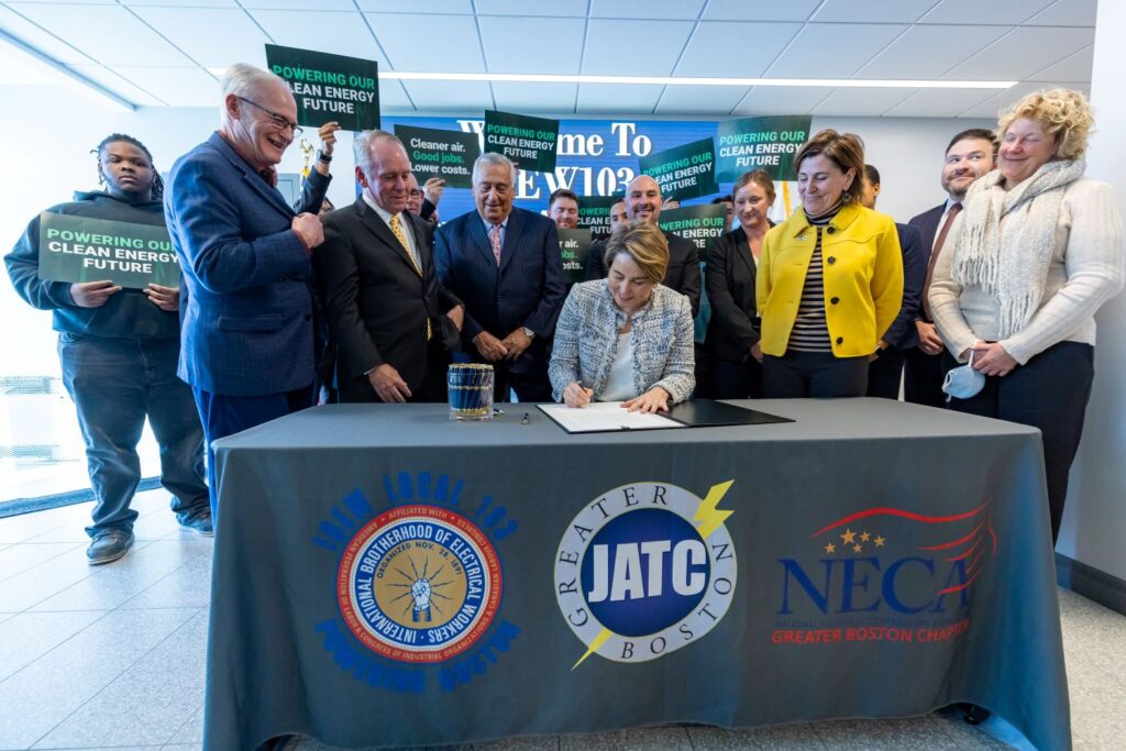 Senator Barrett and others watch as Governor Healey signs the climate bill into law.